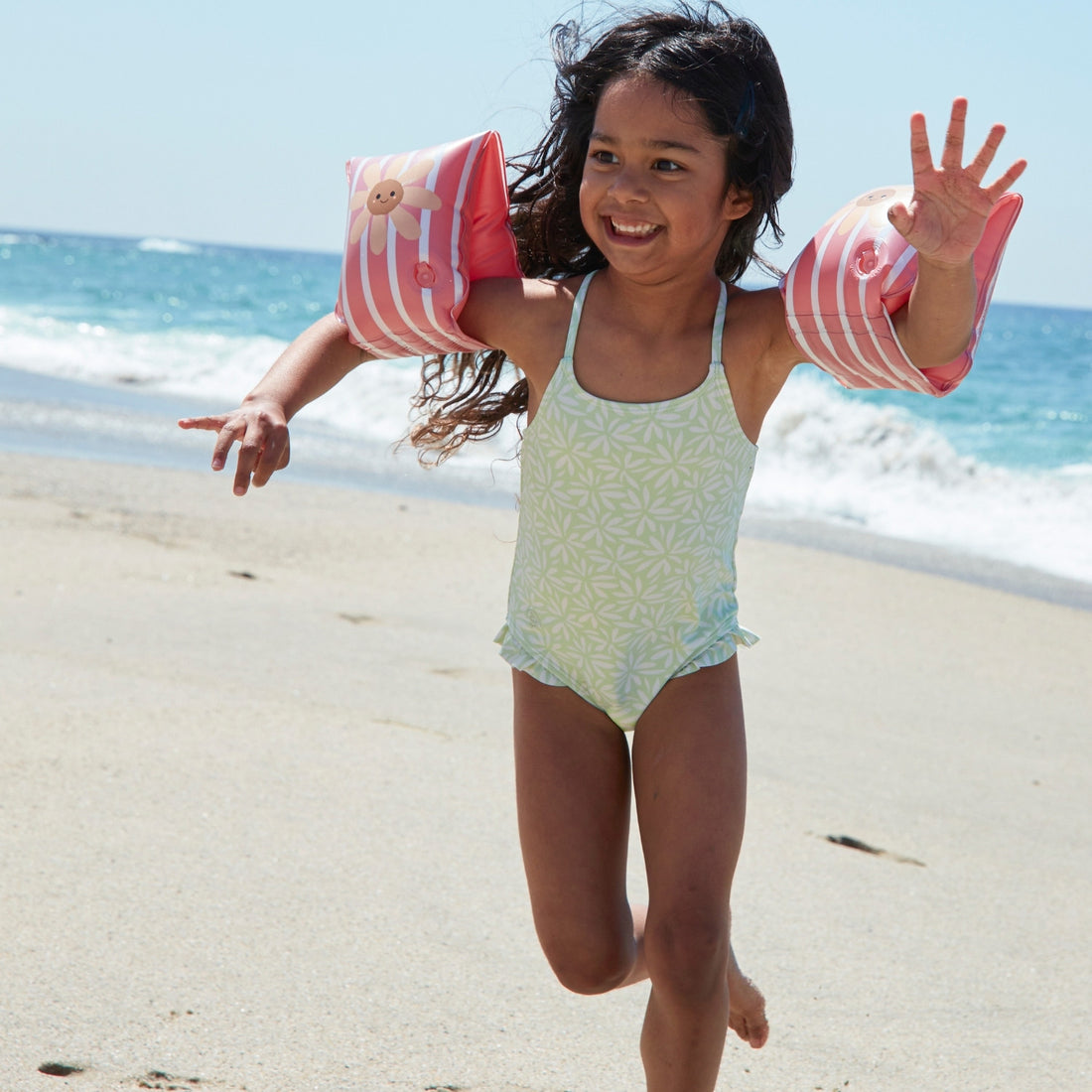 kind spelend op het strand met zwembandjes