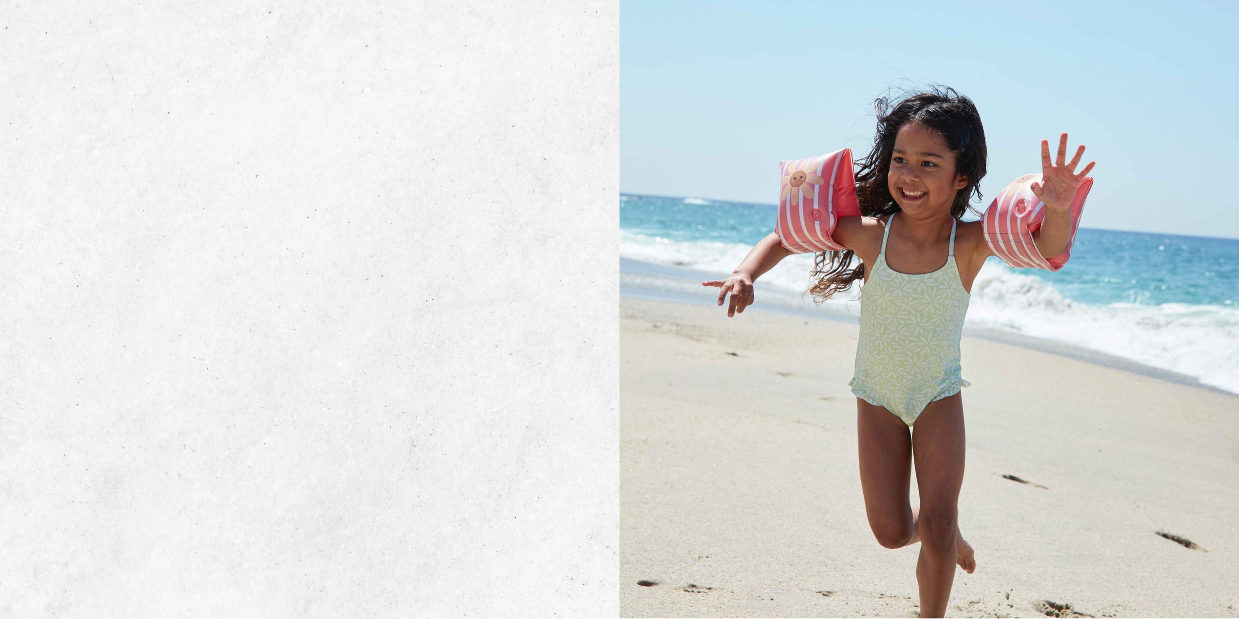 kind speelt op het strand met zwembandjes